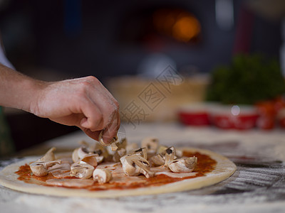 厨师把新鲜蘑菇放厨房桌子上的比萨饼上厨师把新鲜蘑菇放比萨饼上图片