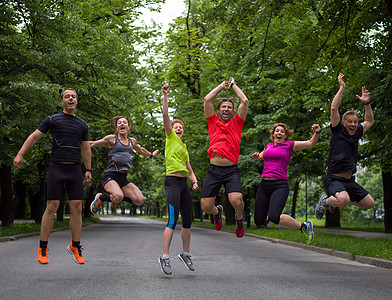 跑步者队早上的训练中空中跳跃群健康的跑步者队早上的训练中城市公园的空中跳跃图片