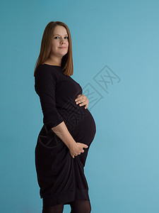 幸福孕妇的肖像,双手放蓝色背景上腹部蓝色背景下孕妇的肖像图片