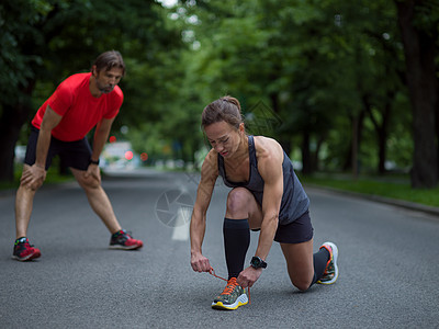 运动女人系跑步鞋鞋带女人系着跑鞋鞋带准备早上城市公园跑步图片
