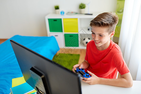 游戏,技术人的微笑男孩与游戏电脑玩电子游戏家里电脑上玩电子游戏的游戏玩家男孩图片