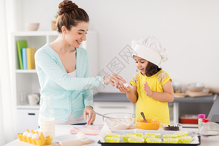 家庭,烹饪,烘焙人们的快乐的母亲小女儿着鸡蛋,家里的厨房纸杯蛋糕快乐的母女家烘焙图片