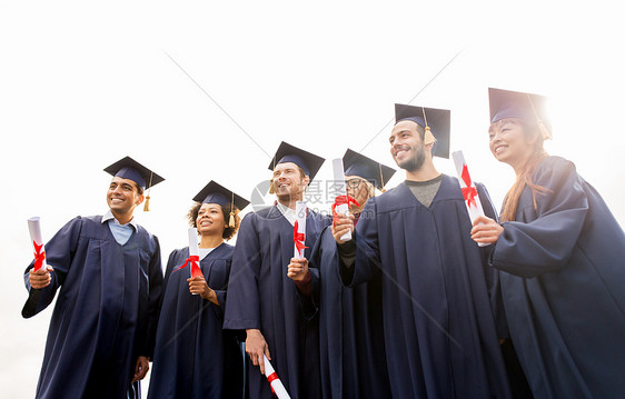 教育,毕业人的群快乐的国际学生迫击炮板学士学位礼服与文凭文凭的迫击炮板上快乐的学生图片