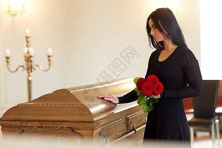 葬礼,人们哀悼的幸的女人带着红玫瑰棺材教堂的葬礼上葬礼上带着红玫瑰棺材的悲伤女人图片
