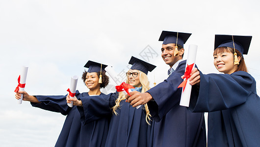 教育,毕业人的群快乐的国际学生迫击炮板学士学位礼服与文凭文凭的迫击炮板上快乐的学生图片