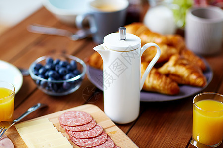 食物热饮早餐时木桌上的咖啡壶早餐时,咖啡壶餐桌上的食物图片