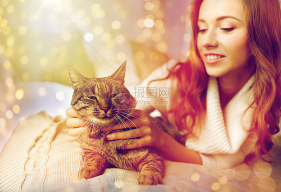 宠物,舒适,休息人的快乐的轻女人猫躺床上家快乐的轻女人,猫躺家里的床上图片