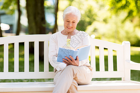 老,退休人们的快乐的老妇女阅读书籍坐长凳上的夏季公园快乐的高级女人夏天公园看书图片