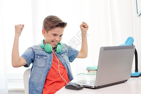 技术,游戏人的带耳机的男孩笔记本电脑上玩电子游戏,并家里庆祝胜利带耳机的男孩笔记本电脑上玩电子游戏图片