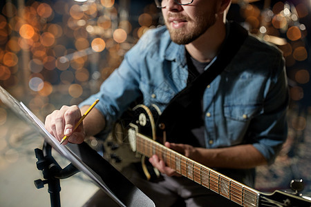 人,艺术娱乐活动男人与吉他写作笔记音乐书工作室假日灯光背景录音室里,吉他写作的男人图片