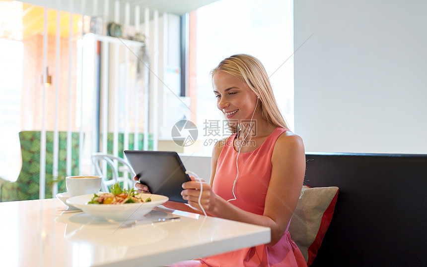 饮食,技术,人休闲快乐的轻妇女与平板电脑电脑,耳机食物餐厅快乐的轻女人餐厅用平板电脑图片