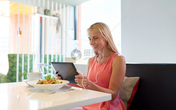饮食,技术,人休闲快乐的轻妇女与平板电脑电脑,耳机食物餐厅快乐的轻女人餐厅用平板电脑图片