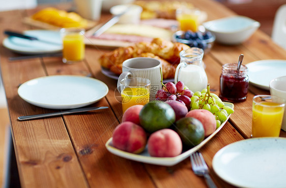食物饮食早餐时木制桌子上的水果橙汁牛奶果酱盘子早餐时桌上的水果果汁其他食物图片