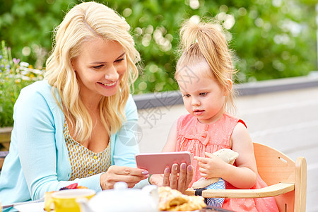 家庭,技术人的快乐的微笑母亲女儿与智能手机咖啡馆餐厅露台母亲女儿咖啡馆着智能手机图片