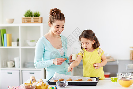 家庭,烘焙,烹饪人们的快乐的母亲小女儿吃饼干与牛奶家里厨房快乐的母亲女儿家吃饼干图片