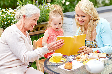 家庭世代人的快乐的母亲与女儿祖母咖啡馆餐馆露台读书咖啡馆里快乐的家庭读物图片