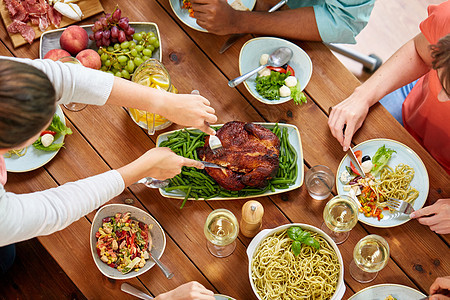感恩节,饮食休闲群人餐桌上吃烤鸡火鸡群人晚餐吃鸡肉背景图片