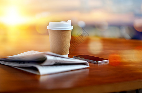 技术,休息,大众媒体新闻咖啡饮料纸杯,智能手机报纸桌子上的灯光背景咖啡杯,智能手机报纸桌子上图片