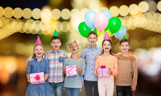 童,生日,友谊人的快乐的微笑孩子戴着派帽,节日的灯光背景下礼物气球生日聚会上带礼物的快乐孩子图片