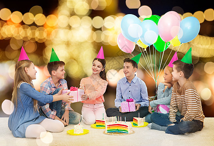 童,节日,庆祝,友谊人的快乐的微笑孩子派帽子与蛋糕送礼物生日聚会上的节日灯光背景快乐的孩子生日聚会上送礼物图片