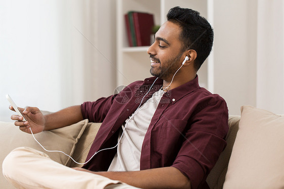 技术,休闲人的快乐的人耳机与智能手机听音乐家戴耳机的人智能手机上听音乐图片