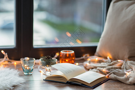 潮湿舒适的家庭书,花环灯蜡烛窗台上窗台上的书花环灯蜡烛图片