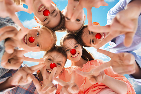 红鼻子日,慈善童的快乐的微笑孩子与小丑鼻子平的手标志,站蓝天背景上的圆圈孩子们红鼻子日表现出平的手征图片