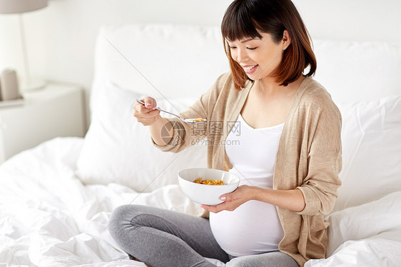 怀孕,人们早餐的快乐的亚洲孕妇家里卧室的床上吃麦片快乐的孕妇家吃麦片图片