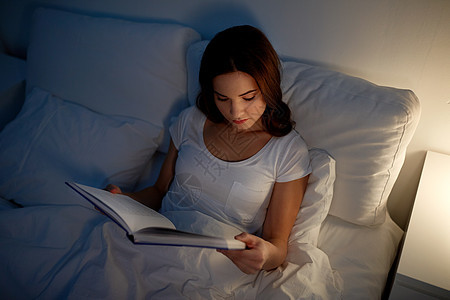 休闲人的轻的女人晚上家床上看书轻的女人晚上家床上看书图片