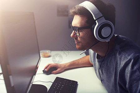 技术,游戏,娱乐活动,让们的游戏人的轻人耳机眼镜与个人电脑玩游戏家里流媒体播放演练视频戴耳机的男人家玩电图片