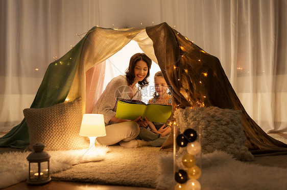 家庭,潮格人的快乐的母亲小女儿孩子们的帐篷里家里晚上看书孩子们家帐篷里快乐的家庭读物图片