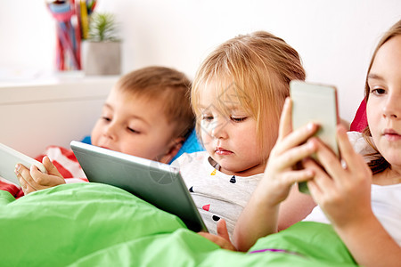 童,技术家庭孩子们家里的床上平板电脑智能手机家里平板电脑的小孩子图片