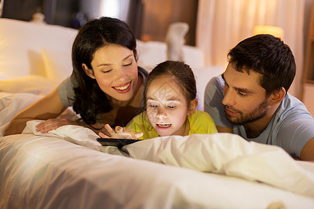 人们家庭的快乐的母亲,父亲小女儿家里晚上床上用平板电脑家庭与平板电脑床上晚上家图片
