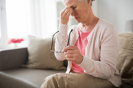 老健康问题视力人的老人戴着眼镜坐沙发上,家头痛戴眼镜的老妇女家头痛图片