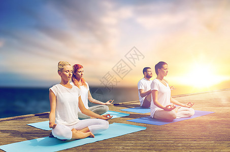 瑜伽健康的生活方式群人海上背景的木墩上冥想莲花姿势人们户外冥想瑜伽莲花姿势图片
