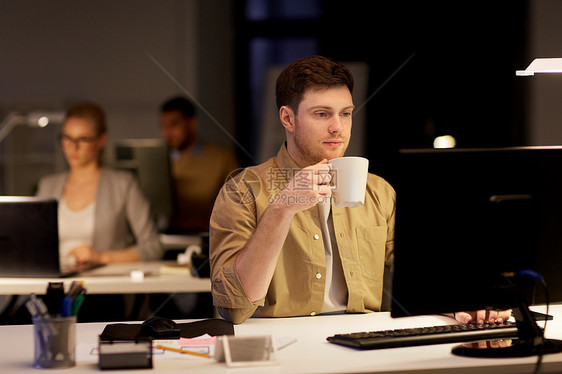 商业,截止日期技术男人电脑工作喝咖啡夜间办公室带笔记本电脑咖啡的男人夜间办公室工作图片