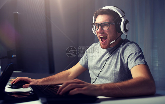 技术,游戏,娱乐活动,让们的游戏人的快乐的笑轻人戴着眼镜,带着耳机家里玩电脑游戏流媒体播放演练视频戴耳机的男人图片
