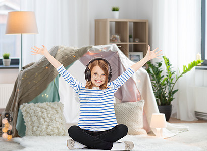 技术人的快乐的女孩戴着耳机家听音乐,孩子们的房间TEPE背景下带耳机的女孩家听音乐图片