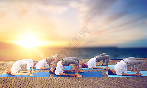 健身,瑜伽健康的生活方式群人海上背景的木墩上桥式户外运动群人户外瑜伽桥姿势图片