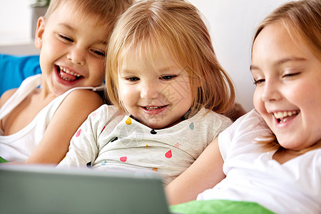 童,技术家庭快乐的孩子与平板电脑电脑床上家快乐的小孩子家里的床上用平板电脑图片