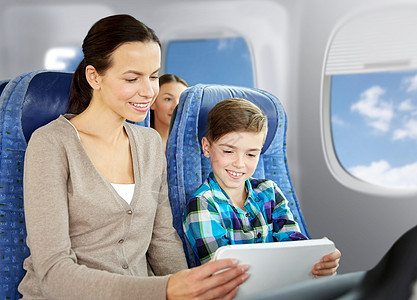 旅行,旅游,家庭技术快乐的母亲儿子与平板电脑电脑坐飞机上的舷窗背景快乐的家庭与平板电脑坐飞机上快乐的家庭与背景图片