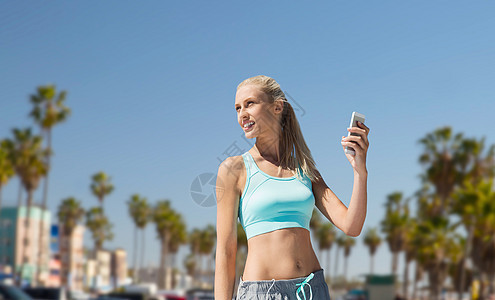健身,运动技术微笑的轻妇女与智能手机锻炼威尼斯海滩背景加利福尼亚智能手机的女人洛杉矶运动智能手机的图片