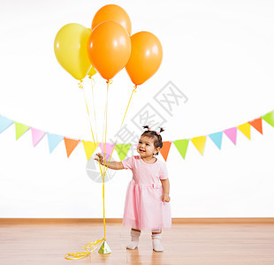 童,人庆祝快乐的女婴与氦气球生日聚会上生日派上带气球的快乐女婴生日派上带气球的快乐女婴图片