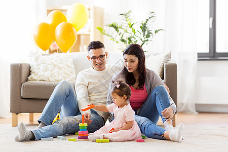 家庭,假期人的快乐的母亲,父亲小女儿家里玩环形金字塔婴儿玩具带着父母玩金字塔玩具的女婴带着父母玩金字塔玩具的图片