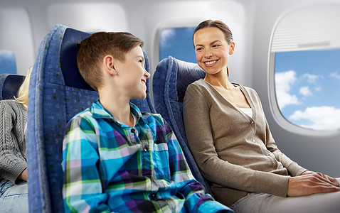 旅行,旅游家庭快乐的母亲儿子坐飞机上,舷窗背景下交谈快乐的母子乘飞机旅行快乐的母子乘飞机旅行图片