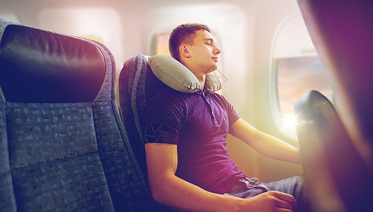 旅行,旅游人的快乐的轻人睡飞机上,充气枕头舷窗背景轻人用旅行枕头睡飞机上轻人用旅行枕头睡飞机上图片
