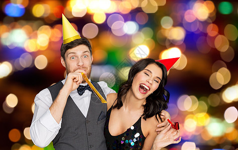 生日,庆祝节日的快乐的夫妇与聚会鼓风机帽子节日的灯光背景下玩得很开心快乐的夫妻派奏者玩得开心快乐的夫妻图片