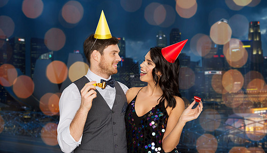 生日,庆祝假期快乐的夫妇与聚会奏帽子新加坡城市夜景灯光背景下玩得很开心快乐的夫妻派奏者玩得开心快乐的图片