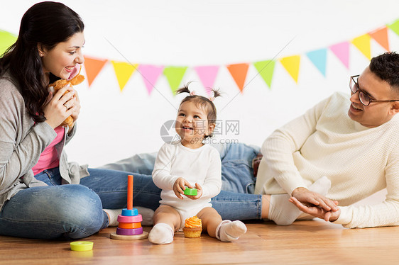 家庭,假期人的快乐的母亲,父亲小女儿生日聚会上玩玩具带着父母玩玩具的女婴带着父母玩玩具的女婴图片