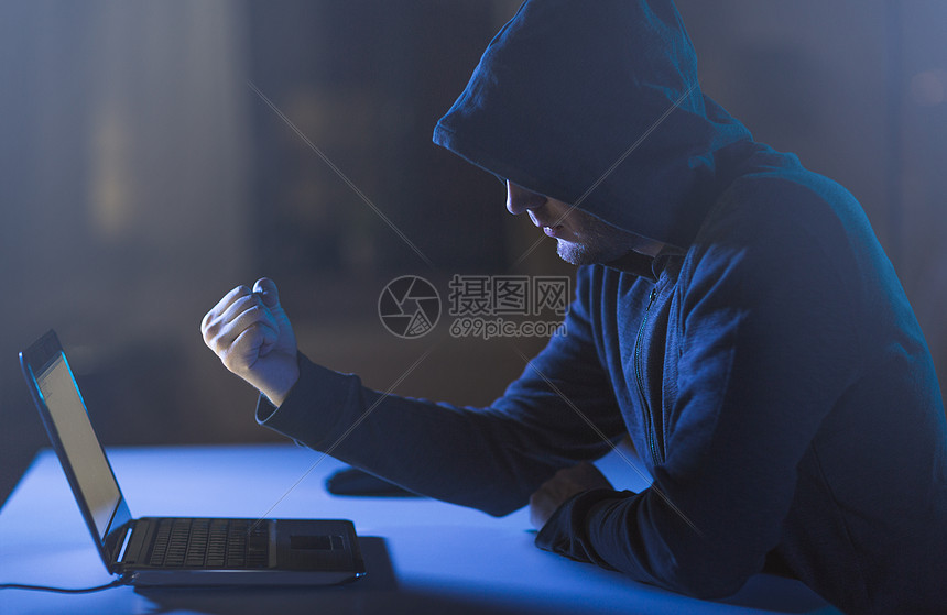 网络犯罪,黑客技术犯罪男黑客黑暗的房间里向笔记本电脑展示拳头黑客黑暗的房间里向笔记本电脑展示拳头黑客黑暗的房图片